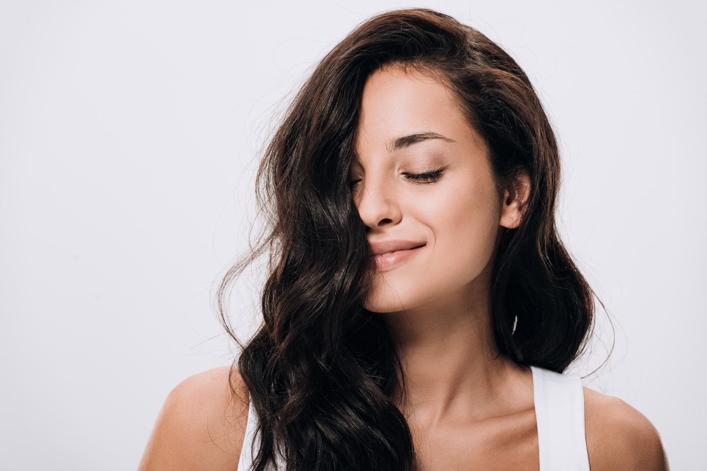 A serene woman with long, wavy, dark hair smiles gently, highlighting her healthy scalp and hair, perfect for illustrating hair rejuvenation services at Serenity MedSpa, emphasizing tips to avoid after PRP hair treatment for optimal results.