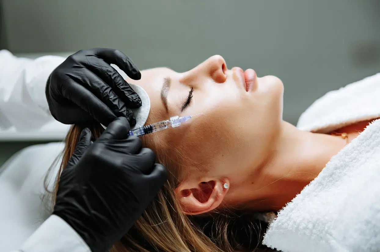 Aesthetic specialist performing a facial injection on a woman to restore volume—commonly done with Radiesse and Sculptra.