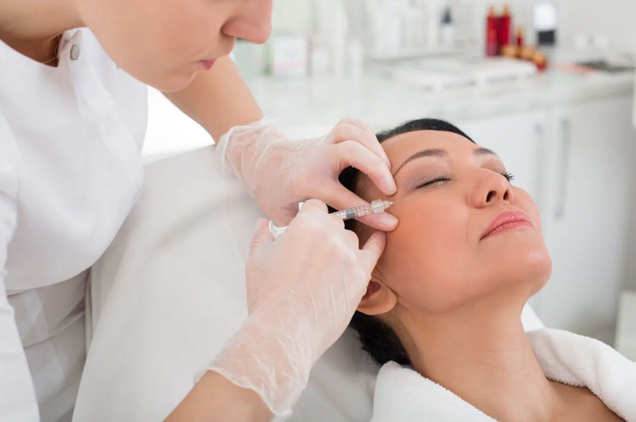 Close-up of a woman receiving a Xeomin and Botox injection near the eye area to smooth fine lines and wrinkles.