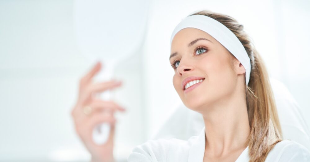 Woman in a spa robe admiring her smooth, refreshed skin